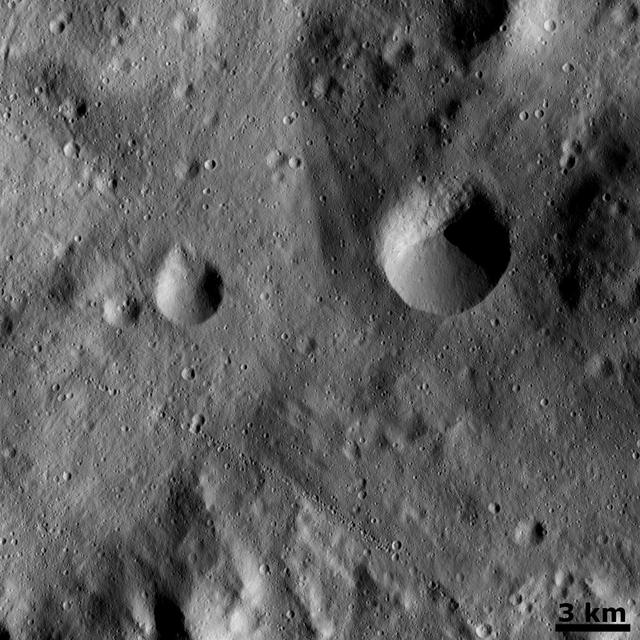 This image from NASA Dawn spacecraft show a slightly curved chain of small craters in the bottom half of the image. This chain is located on the floor of asteroid Vesta large south-polar impact structure, Rheasilvia.