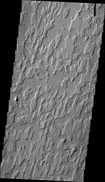 The unusual texture in this image from NASA 2001 Mars Odyssey spacecraft is located on the plains of Elysium Planitia. The surface appears to be layered. The top layer has parallel, linear hills and channels.