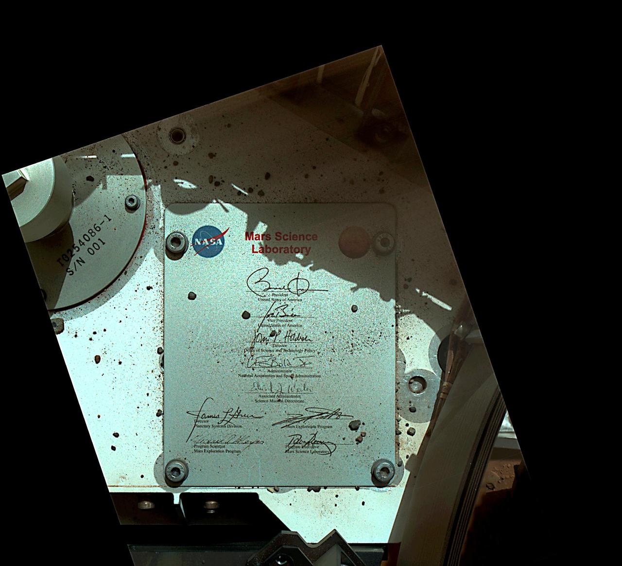 This view of Curiosity deck shows a plaque bearing several signatures of US officials, including that of President Obama and Vice President Biden. The image was taken by the rover Mars Hand Lens Imager MAHLI.