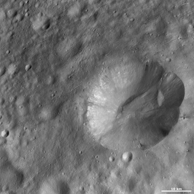 This image from NASA Dawn spacecraft is located in Marcia quadrangle, just south of Vesta equator. It has a scalloped shaped rim and the top part of the rim is more degraded than the rest.