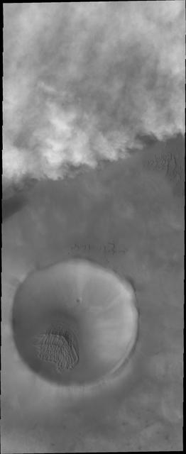 This image from NASA 2001 Mars Odyssey captures storm clouds that are moving towards the crater in the bottom of this image. Storms like this are common during the spring and early summer near the north pole.