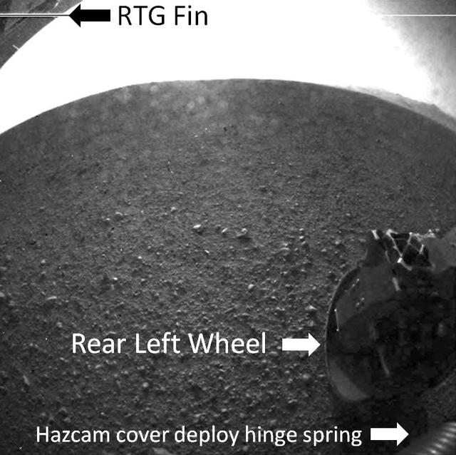 This labeled version of one of the first images taken by a rear Hazard-Avoidance camera on NASA Curiosity rover shows a fin on the radioisotope thermoelectric generator, the rear left wheel and a spring that released the dust cover.