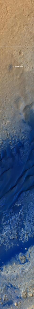 This color-enhanced view, taken by NASA Mars Reconnaissance Orbiter as the satellite flew overhead, shows the terrain around the Curiosity landing site within Gale Crater on Mars. The rover is seen as the circular object.
