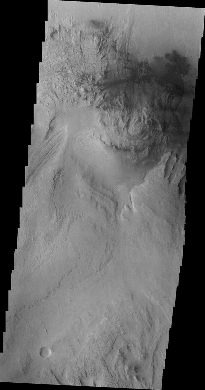 Continuing westward, this image from NASA Mars Odyssey spacecraft shows Mt. Sharp just east of the highest peak of the deposit. The dark material near the top of the image is likely sand. This image shows the dark material on the floor and on Mt. Sharp.