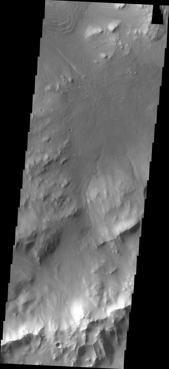 This image from NASA Mars Odyssey spacecraft shows the southeastern rim of Gale Crater. The large ridge at the bottom of image is the top of the rim. Image shows a channel dissecting the rim; two dune fields occur along the path of the channel too.