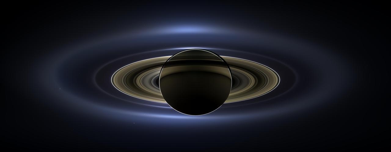 On July 19, 2013, in an event celebrated the world over, NASA's Cassini spacecraft slipped into Saturn's shadow and turned to image the planet, seven of its moons, its inner rings -- and, in the background, our home planet, Earth.  With the sun's powerful and potentially damaging rays eclipsed by Saturn itself, Cassini's onboard cameras were able to take advantage of this unique viewing geometry. They acquired a panoramic mosaic of the Saturn system that allows scientists to see details in the rings and throughout the system as they are backlit by the sun. This mosaic is special as it marks the third time our home planet was imaged from the outer solar system; the second time it was imaged by Cassini from Saturn's orbit; and the first time ever that inhabitants of Earth were made aware in advance that their photo would be taken from such a great distance.  With both Cassini's wide-angle and narrow-angle cameras aimed at Saturn, Cassini was able to capture 323 images in just over four hours. This final mosaic uses 141 of those wide-angle images. Images taken using the red, green and blue spectral filters of the wide-angle camera were combined and mosaicked together to create this natural-color view. A brightened version with contrast and color enhanced (Figure 1), a version with just the planets annotated (Figure 2), and an annotated version (Figure 3) are shown above.  This image spans about 404,880 miles (651,591 kilometers) across.  The outermost ring shown here is Saturn's E ring, the core of which is situated about 149,000 miles (240,000 kilometers) from Saturn. The geysers erupting from the south polar terrain of the moon Enceladus supply the fine icy particles that comprise the E ring; diffraction by sunlight gives the ring its blue color. Enceladus (313 miles, or 504 kilometers, across) and the extended plume formed by its jets are visible, embedded in the E ring on the left side of the mosaic.  At the 12 o'clock position and a bit inward from the E ring lies the barely discernible ring created by the tiny, Cassini-discovered moon, Pallene (3 miles, or 4 kilometers, across). (For more on structures like Pallene's ring, see PIA08328). The next narrow and easily seen ring inward is the G ring. Interior to the G ring, near the 11 o'clock position, one can barely see the more diffuse ring created by the co-orbital moons, Janus (111 miles, or 179 kilometers, across) and Epimetheus (70 miles, or 113 kilometers, across). Farther inward, we see the very bright F ring closely encircling the main rings of Saturn.  Following the outermost E ring counter-clockwise from Enceladus, the moon Tethys (662 miles, or 1,066 kilometers, across) appears as a large yellow orb just outside of the E ring. Tethys is positioned on the illuminated side of Saturn; its icy surface is shining brightly from yellow sunlight reflected by Saturn. Continuing to about the 2 o'clock position is a dark pixel just outside of the G ring; this dark pixel is Saturn's Death Star moon, Mimas (246 miles, or 396 kilometers, across). Mimas appears, upon close inspection, as a very thin crescent because Cassini is looking mostly at its non-illuminated face.  The moons Prometheus, Pandora, Janus and Epimetheus are also visible in the mosaic near Saturn's bright narrow F ring. Prometheus (53 miles, or 86 kilometers, across) is visible as a faint black dot just inside the F ring and at the 9 o'clock position. On the opposite side of the rings, just outside the F ring, Pandora (50 miles, or 81 kilometers, across) can be seen as a bright white dot. Pandora and Prometheus are shepherd moons and gravitational interactions between the ring and the moons keep the F ring narrowly confined. At the 11 o'clock position in between the F ring and the G ring, Janus (111 miles, or 179 kilometers, across) appears as a faint black dot. Janus and Prometheus are dark for the same reason Mimas is mostly dark: we are looking at their non-illuminated sides in this mosaic. Midway between the F ring and the G ring, at about the 8 o'clock position, is a single bright pixel, Epimetheus. Looking more closely at Enceladus, Mimas and Tethys, especially in the brightened version of the mosaic, one can see these moons casting shadows through the E ring like a telephone pole might cast a shadow through a fog.  In the non-brightened version of the mosaic, one can see bright clumps of ring material orbiting within the Encke gap near the outer edge of the main rings and immediately to the lower left of the globe of Saturn. Also, in the dark B ring within the main rings, at the 9 o'clock position, one can see the faint outlines of two spoke features, first sighted by NASA's Voyager spacecraft in the early 1980s and extensively studied by Cassini.  Finally, in the lower right of the mosaic, in between the bright blue E ring and the faint but defined G ring, is the pale blue dot of our planet, Earth. Look closely and you can see the moon protruding from the Earth's lower right. (For a higher resolution view of the Earth and moon taken during this campaign, see PIA14949.) Earth's twin, Venus, appears as a bright white dot in the upper left quadrant of the mosaic, also between the G and E rings. Mars also appears as a faint red dot embedded in the outer edge of the E ring, above and to the left of Venus.  For ease of visibility, Earth, Venus, Mars, Enceladus, Epimetheus and Pandora were all brightened by a factor of eight and a half relative to Saturn. Tethys was brightened by a factor of four. In total, 809 background stars are visible and were brightened by a factor ranging from six, for the brightest stars, to 16, for the faintest. The faint outer rings (from the G ring to the E ring) were also brightened relative to the already bright main rings by factors ranging from two to eight, with the lower-phase-angle (and therefore fainter) regions of these rings brightened the most. The brightened version of the mosaic was further brightened and contrast-enhanced all over to accommodate print applications and a wide range of computer-screen viewing conditions.  Some ring features -- such as full rings traced out by tiny moons -- do not appear in this version of the mosaic because they require extreme computer enhancement, which would adversely affect the rest of the mosaic. This version was processed for balance and beauty.  This view looks toward the unlit side of the rings from about 17 degrees below the ring plane. Cassini was approximately 746,000 miles (1.2 million kilometers) from Saturn when the images in this mosaic were taken. Image scale on Saturn is about 45 miles (72 kilometers) per pixel.  This mosaic was made from pictures taken over a span of more than four hours while the planets, moons and stars were all moving relative to Cassini. Thus, due to spacecraft motion, these objects in the locations shown here were not in these specific places over the entire duration of the imaging campaign. Note also that Venus appears far from Earth, as does Mars, because they were on the opposite side of the sun from Earth.  http://photojournal.jpl.nasa.gov/catalog/PIA17172