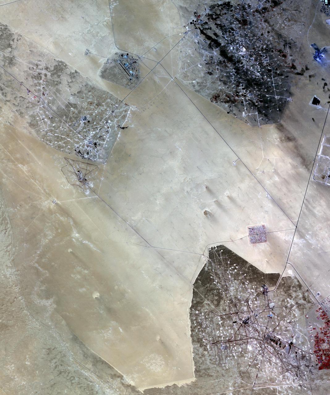 In the desert of southern Kuwait, three oil fields spread out across the empty landscape as seen by NASA Terra spacecraft.