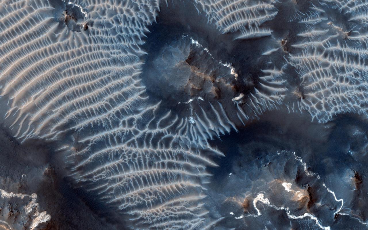 This colorful scene is situated in the Noctis Labyrinthus, perched high on the Tharsis rise in the upper reaches of the Valles Marineris canyon system as seen by NASA Mars Reconnaissance Orbiter.