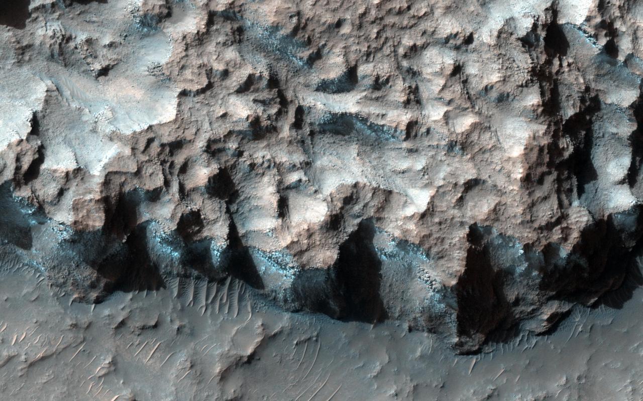 A south-facing escarpment in the Northwest Hellas region that was targeted for the phyllosilicates shows instances of bluish rock in this enhanced color image taken by NASA Mars Reconnaissance Orbiter.