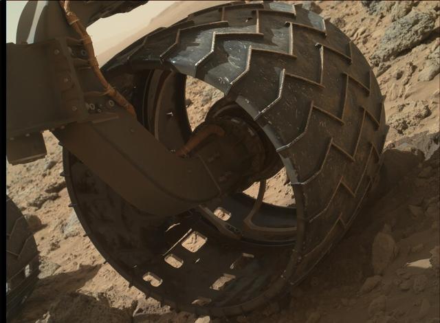 The left-front wheel of NASA Curiosity Mars rover shows dents and holes in this image taken by the MAHLI camera, which is mounted at the end of Curiosity robotic arm.