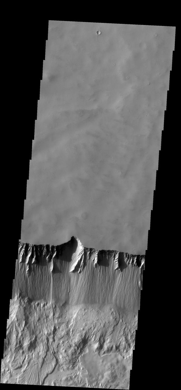 The steep northern wall of Tithonium Chasma crosses this image from NASA 2001 Mars Odyssey spacecraft. Landslide deposits from slope failure can be seen at the lower left corner of the image.