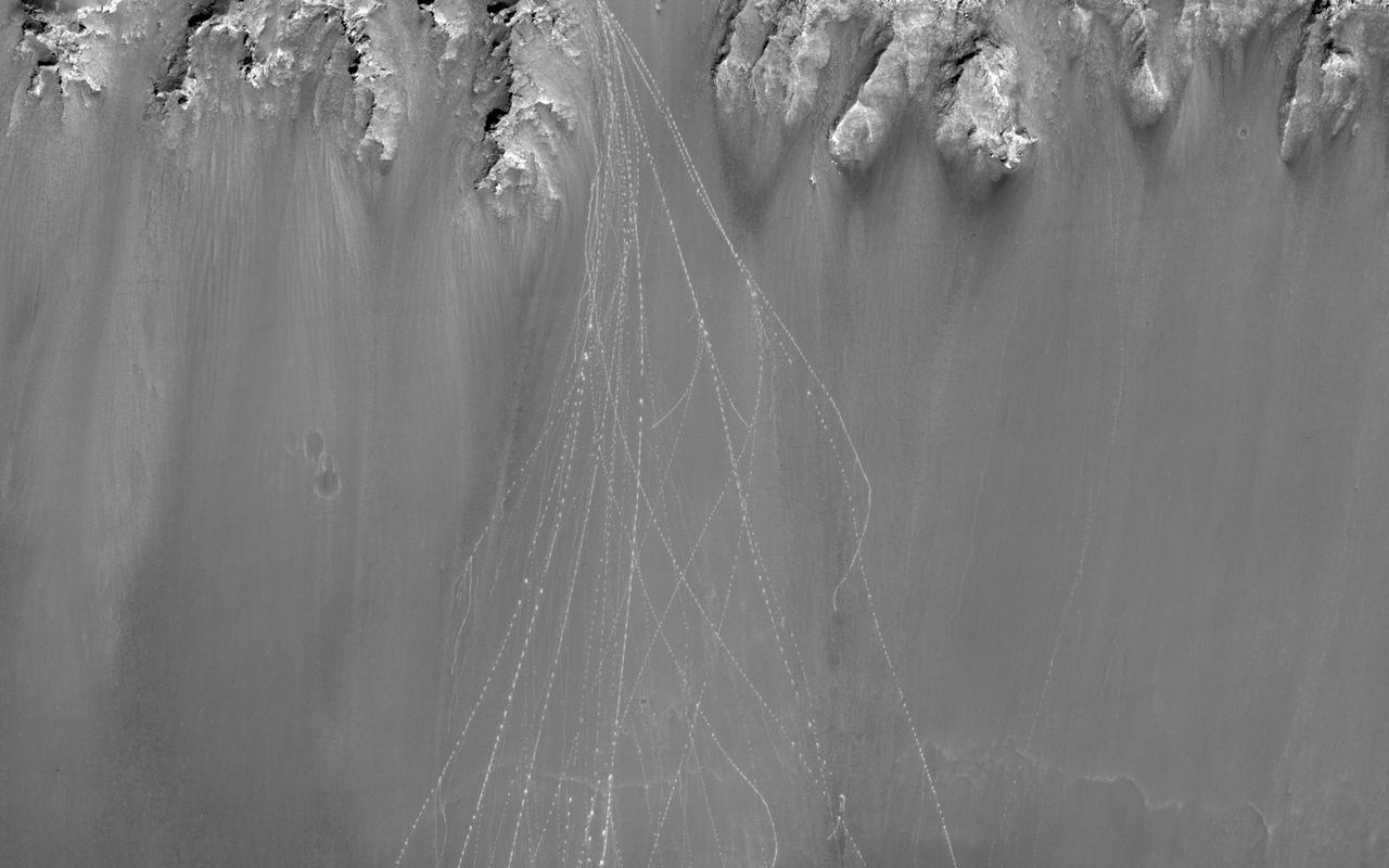 When boulders roll down a dusty Martian slope, they can leave long, dotted tracks behind on the slope surface as seen in this observation from NASA Mars Reconnaissance Orbiter.