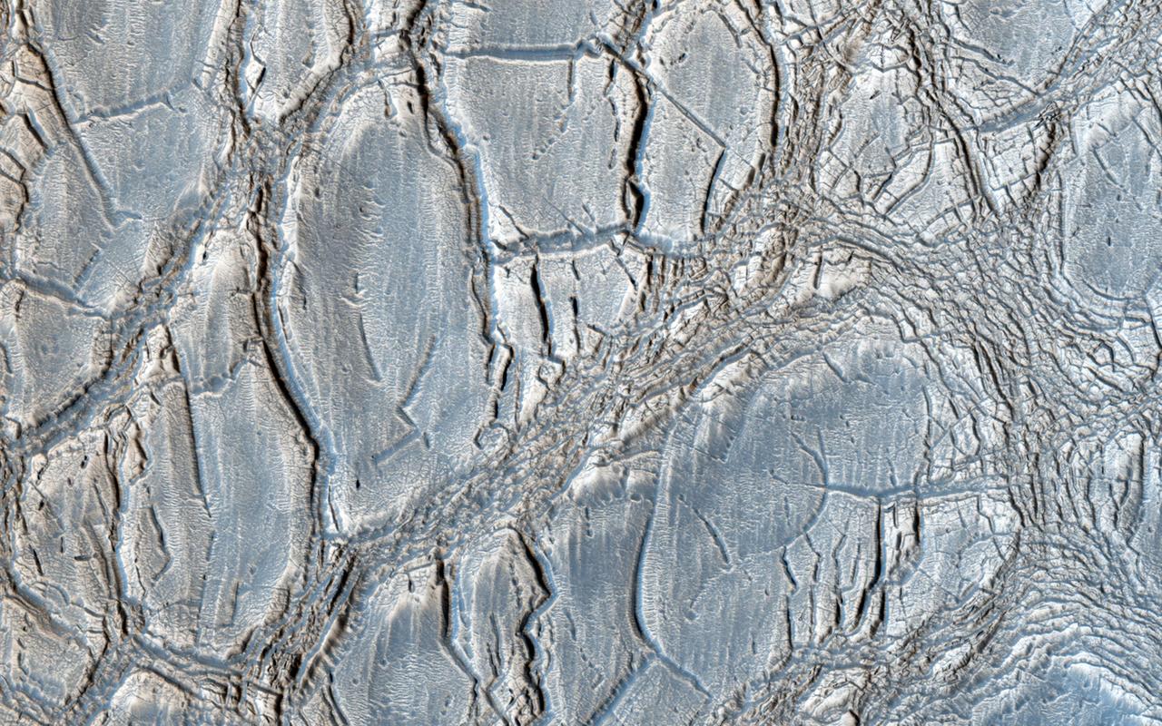 With its cracked, blistery appearance, this mound near the center of a very large, over 5-kilometer diameter mid-latitude crater poses an interesting question: how did this form? This image is from NASA Mars Reconnaissance Orbiter.
