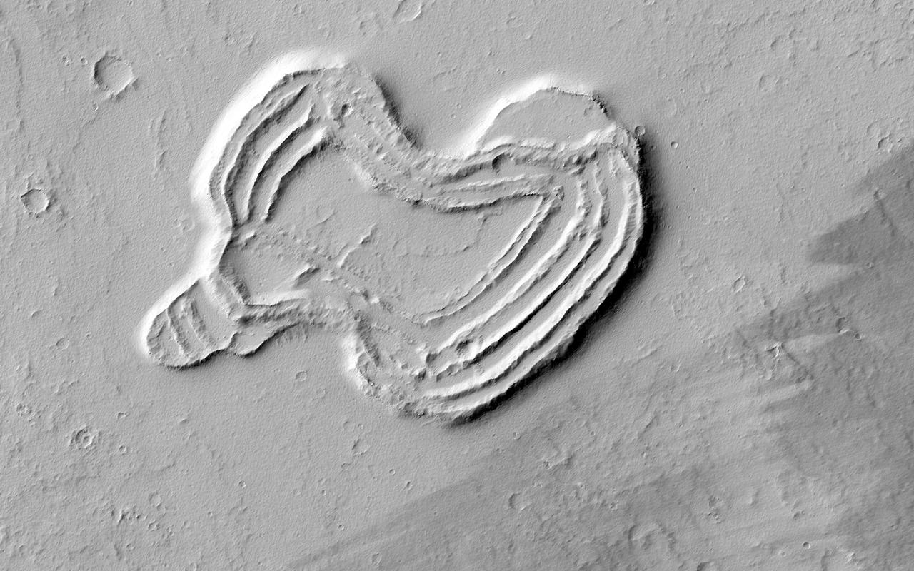 This feature from NASA Mars Reconnaissance Orbiter looks like a heart. It is located south of Ascraeus Mons, which is a large volcano within the Tharsis volcanic plateau, making it extremely likely that this feature was formed by a volcanic process.