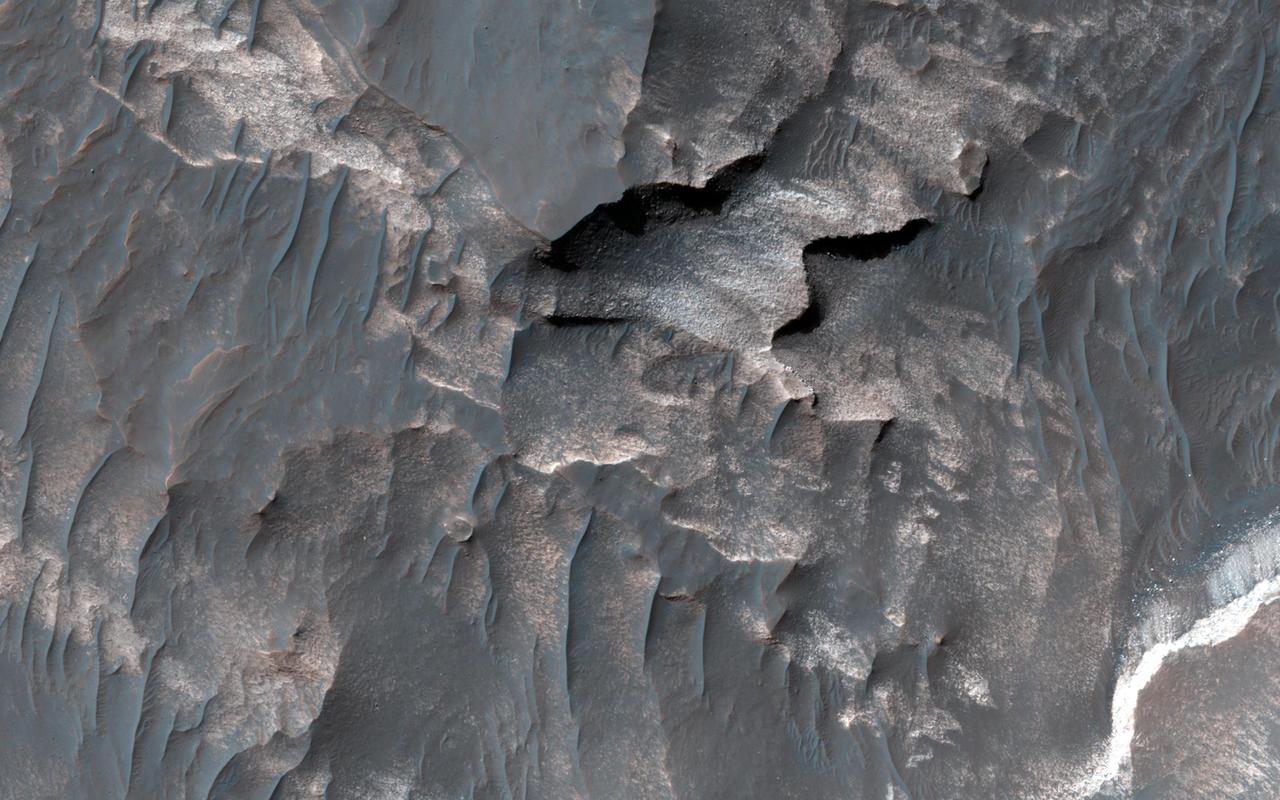 NASA Mars Reconnaissance Orbiter shows light-toned deposits along Coprates Chasma slopes.