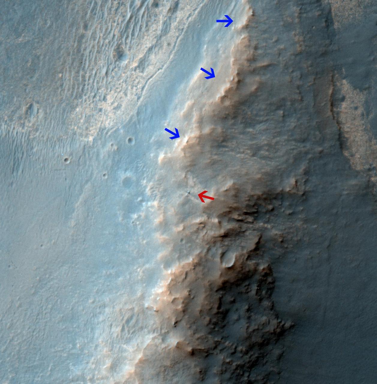 NASA Mars Reconnaissance Orbiter caught this view of NASA Mars Exploration Rover Opportunity on Feb. 14, 2014. The red arrow points to Opportunity at the center of the image. Blue arrows point to tracks left by the rover in October 2013.