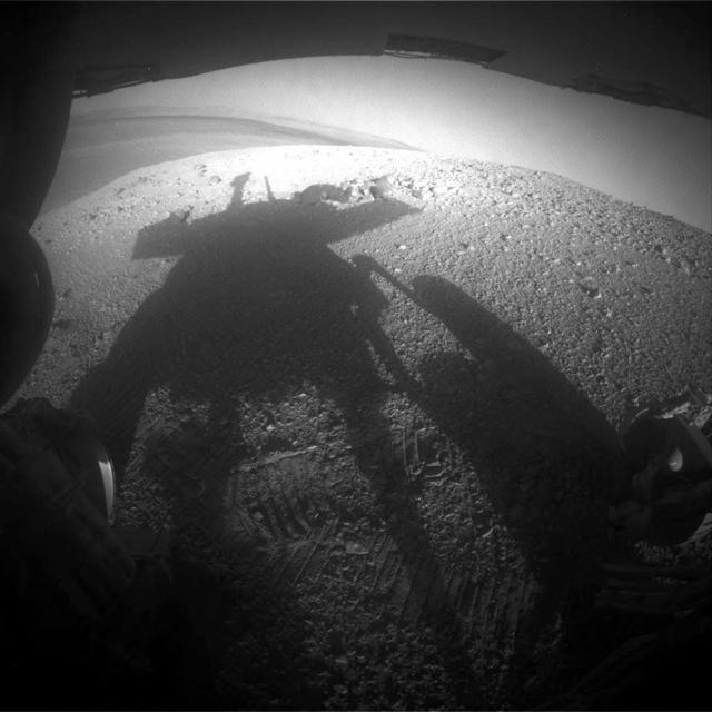 NASA Mars Exploration Rover Opportunity caught its own silhouette in this late-afternoon image from the rover rear HAZCAM on Mar, 20, 2014; its shadow falls across a slope called McClure-Beverlin Escarpment on the western rim of Endeavour Crater.