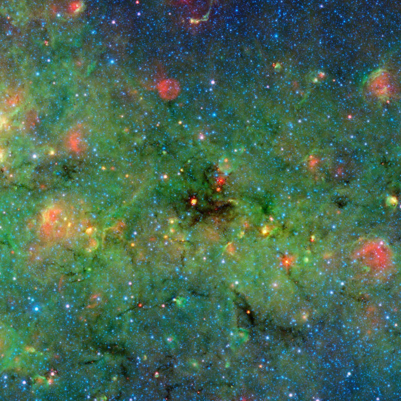 Astronomers have found cosmic clumps so dark, dense and dusty that they throw the deepest shadows ever recorded. A large cloud looms in the center of this image of the galactic plane from NASA Spitzer Space Telescope.