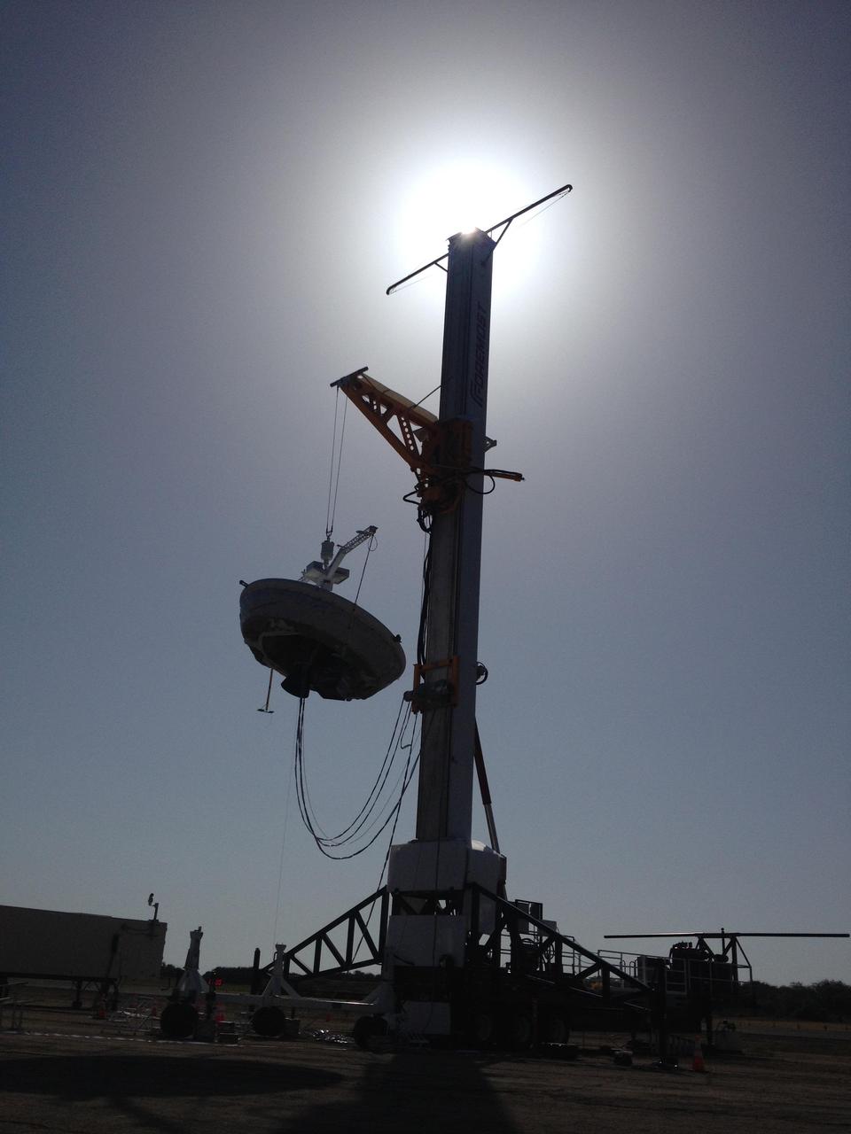 A saucer-shaped vehicle part of NASA Low-Density Supersonic Decelerator LDSD project designed to test interplanetary landing devices hangs on a tower in preparation for launch at the Pacific Missile Range Facility in Kauai, Hawaii.