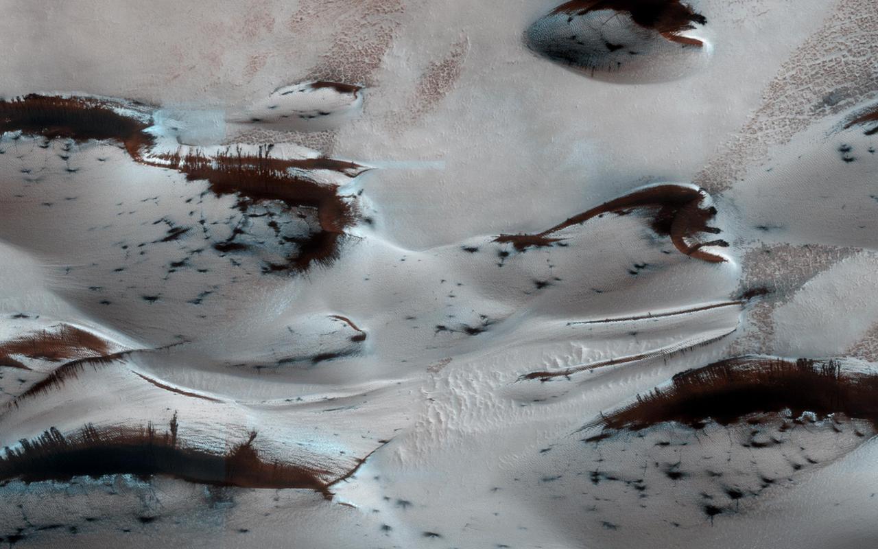 NASA Mars Reconnaissance Orbiter shows Mars northern-most sand dunes beginning to emerge from their winter cover of seasonal carbon dioxide dry ice. Dark, bare south-facing slopes are soaking up the warmth of the sun.