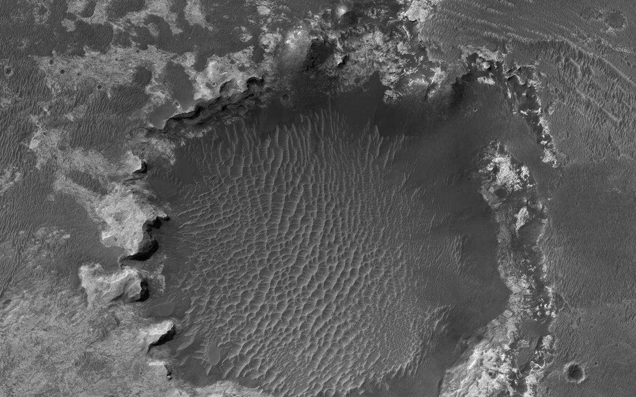 NASA Mars Reconnaissance Orbiter spies an impact crater located in northern Sinus Meridiani has formed along the boundary of two different terrain units.