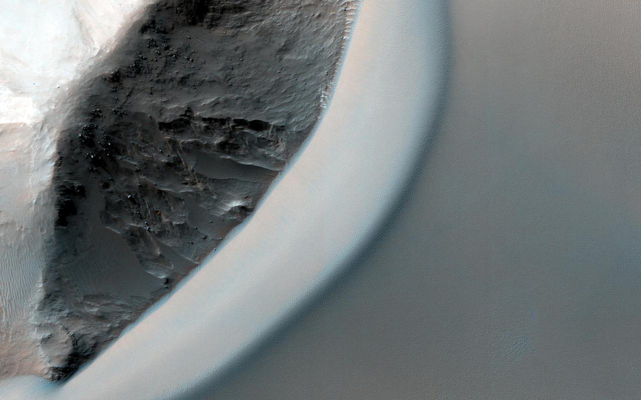 This dramatic image observed by NASA Mars Reconnaissance Orbiter shows dark rippled bodies of sand, sometimes in the form of dunes, streaming through Ganges Chasma. The floor of the canyon is covered by hills and mesas.