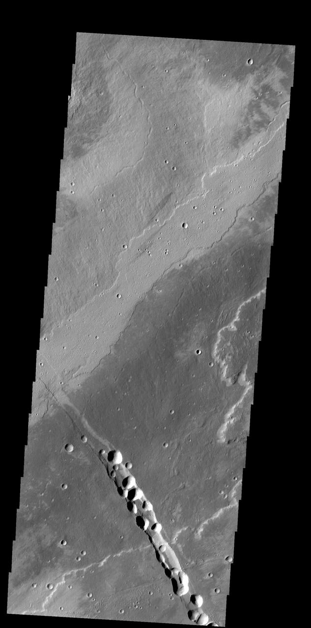 This image from NASA 2001 Mars Odyssey spacecraft shows a small portion of the lava flows from Alba Mons. The depression and collapse features within it are part of the large system of tectonic features created by the apparent collapse of the volcano.
