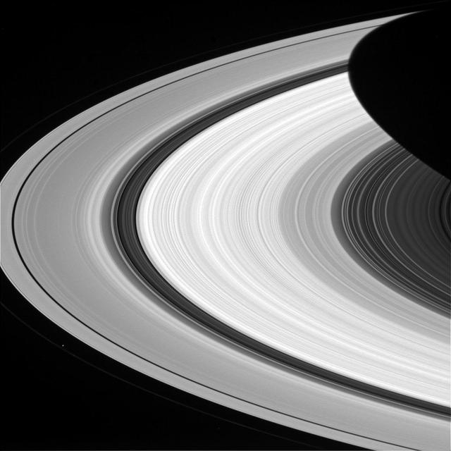 From afar, Saturn's rings look like a solid, homogenous disk of material. But upon closer examination from Cassini, we see that there are varied structures in the rings at almost every scale imaginable. Structures in the rings can be caused by many things, but often times Saturn's many moons are the culprits. The dark gaps near the left edge of the A ring (the broad, outermost ring here) are caused by the moons (Pan and Daphnis) embedded in the gaps, while the wider Cassini division (dark area between the B ring and A ring here) is created by a resonance with the medium-sized moon Mimas (which orbits well outside the rings). Prometheus is seen orbiting just outside the A ring in the lower left quadrant of this image; the F ring can be faintly seen to the left of Prometheus. This view looks toward the sunlit side of the rings from about 15 degrees above the ringplane. The image was taken in red light with the Cassini spacecraft wide-angle camera on Jan. 8, 2015. The view was obtained at a distance of approximately 566,000 miles (911,000 kilometers) from Saturn and at a Sun-Saturn-spacecraft, or phase, angle of 37 degrees. Image scale is 34 miles (54 kilometers) per pixel. http://photojournal.jpl.nasa.gov/catalog/pia18308