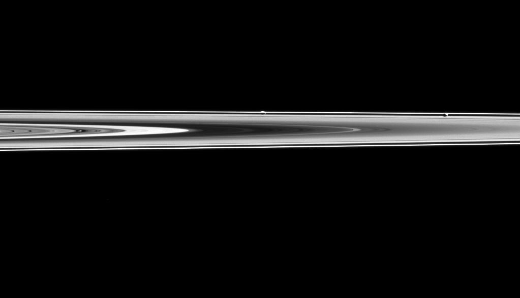 Prometheus and Pandora are almost hidden in Saturn's rings in this image.  Prometheus (53 miles or 86 kilometers across) and Pandora (50 miles or 81 kilometers across) orbit along side Saturn's narrow F ring, which is shaped, in part, by their gravitational influences help to shape that ring. Their proximity to the rings also means that they often lie on the same line of sight as the rings, sometimes making them difficult to spot.  In this image, Prometheus is the left most moon in the ring plane, roughly in the center of the image. Pandora is towards the right.  This view looks toward the unilluminated side of the rings from about 0.3 degrees below the ring plane. The image was taken in visible light with the Cassini spacecraft narrow-angle camera on May 6, 2015.  The view was obtained at a distance of approximately 994,000 miles (1.6 million kilometers) from Prometheus and at a Sun-Prometheus-spacecraft, or phase, angle of 106 degrees. Image scale is 6 miles (10 kilometers) per pixel.  http://photojournal.jpl.nasa.gov/catalog/PIA18334