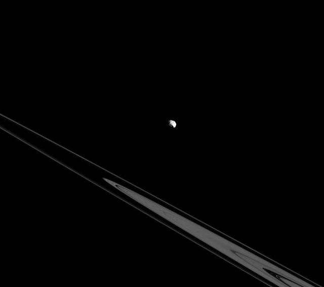 Although Epimetheus appears to be lurking above the rings here, it's actually just an illusion resulting from the viewing angle. In reality, Epimetheus and the rings both orbit in Saturn's equatorial plane. Inner moons and rings orbit very near the equatorial plane of each of the four giant planets in our solar system, but more distant moons can have orbits wildly out of the equatorial plane. It has been theorized that the highly inclined orbits of the outer, distant moons are remnants of the random directions from which they approached the planets they orbit. This view looks toward the unilluminated side of the rings from about -0.3 degrees below the ringplane. The image was taken in visible light with the Cassini spacecraft narrow-angle camera on July 26, 2015. The view was obtained at a distance of approximately 500,000 miles (800,000 kilometers) from Epimetheus and at a Sun-Epimetheus-spacecraft, or phase, angle of 62 degrees. Image scale is 3 miles (5 kilometers) per pixel. http://photojournal.jpl.nasa.gov/catalog/PIA18342
