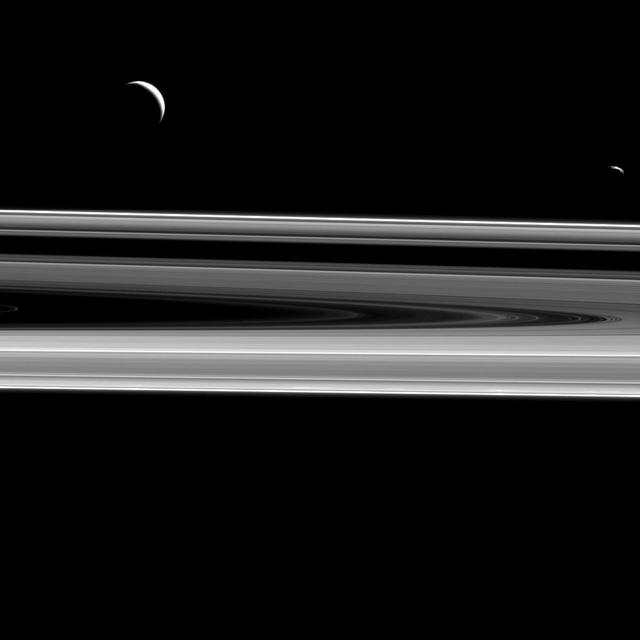 Two moons hover above the rings from this perspective, Enceladus 313 miles or 504 kilometers across, at left, and Janus 111 miles or 179 kilometers across, at right as seen by NASA Cassini spacecraft.