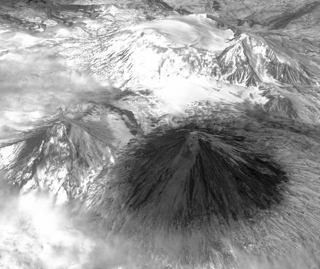 Winter still grips the volcanoes on Russia Kamchatka peninsula. NASA Terra spacecraft acquired this image showing the mantle of white, disturbed by dark ash entirely covering Sheveluch volcano from recent eruptions.