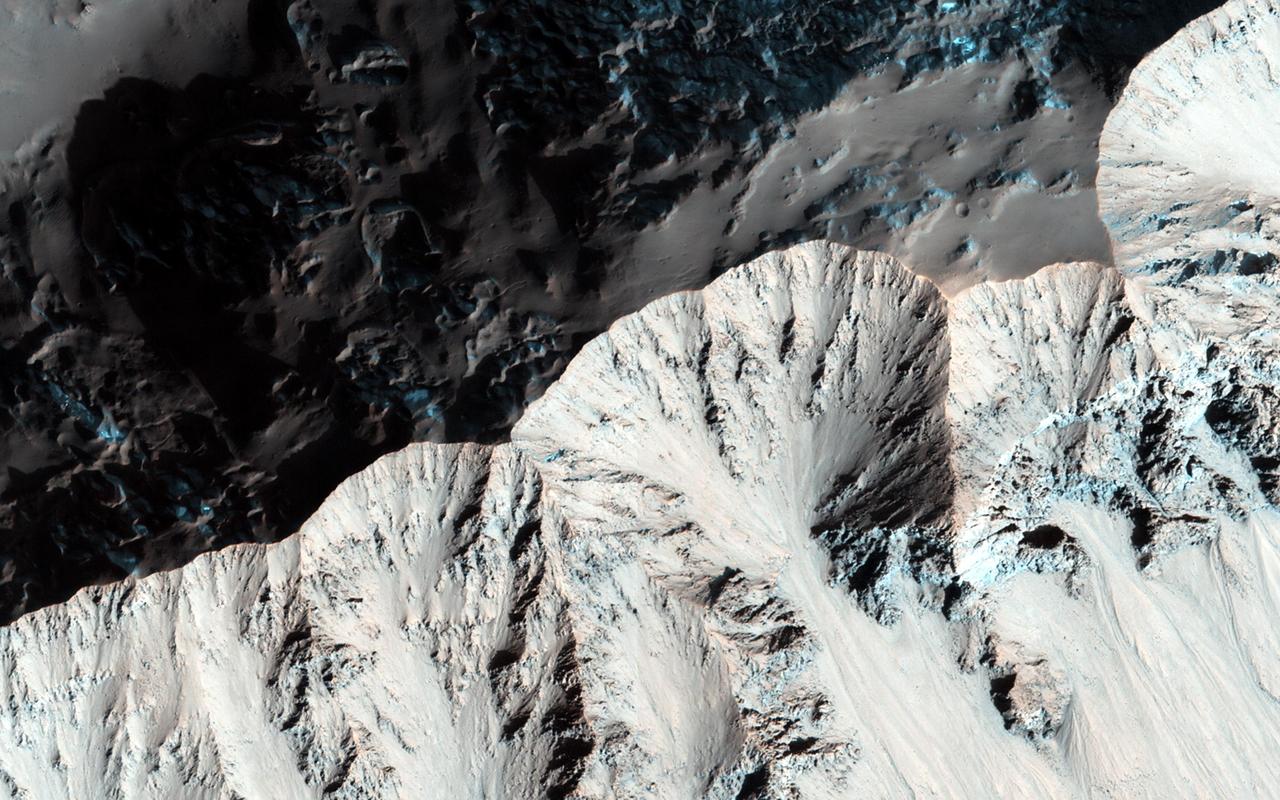 Right past the sharp, but warped rim of this ancient impact crater are deposits of winter frost, which show up as blue in enhanced color as seen by NASA Mars Reconnaissance Orbiter.