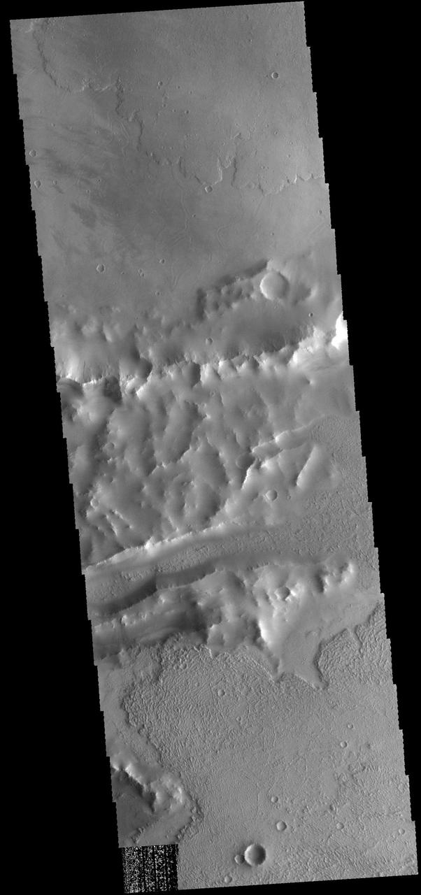 Lava flows of Daedalia Planum can be seen at the top and bottom portions of this image from NASA 2001 Mars Odyssey spacecraft. The ridge and linear depression in the central part of the image are part of Mangala Fossa, a fault bounded graben.