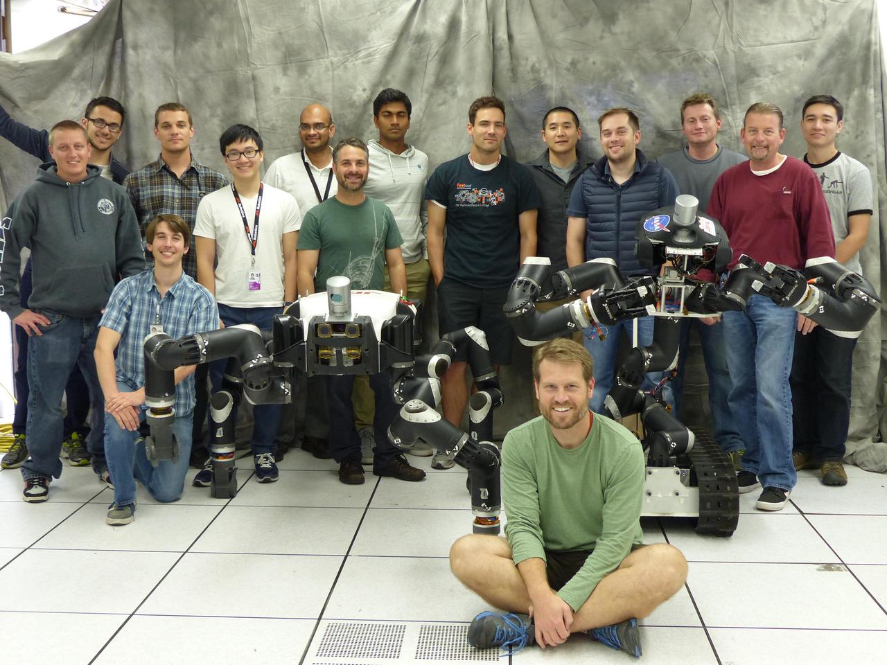 Robotics researchers at NASA Jet Propulsion Laboratory in Pasadena, California, stand with robots RoboSimian and Surrogate, both built at JPL.