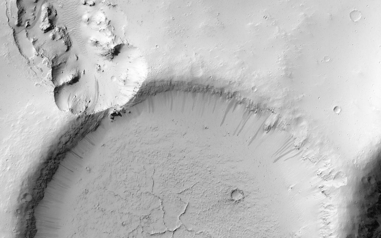 This image NASA Mars Reconnaissance Orbiter shows an impact crater that was cut by lava in the Elysium Planitia region of Mars. It looks relatively flat, with a shallow floor, rough surface texture, and possible cooling cracks seem to indicate that the crater was partially filled with lava. The northern part of the image also shows a more extensive lava flow deposit that surrounds the impact ejecta of the largest impact crater in the image.  Which way did the lava flow? It might appear that the lava flowed from the north through the channel into the partially filled crater. However, if you look at the anaglyph with your red and blue 3D glasses, it becomes clear that the partially filled crater sits on top of the large crater's ejecta blanket, making it higher than the lava flow to the north. Since lava does not flow uphill, that means the explanation isn't so simple.  http://photojournal.jpl.nasa.gov/catalog/PIA18887