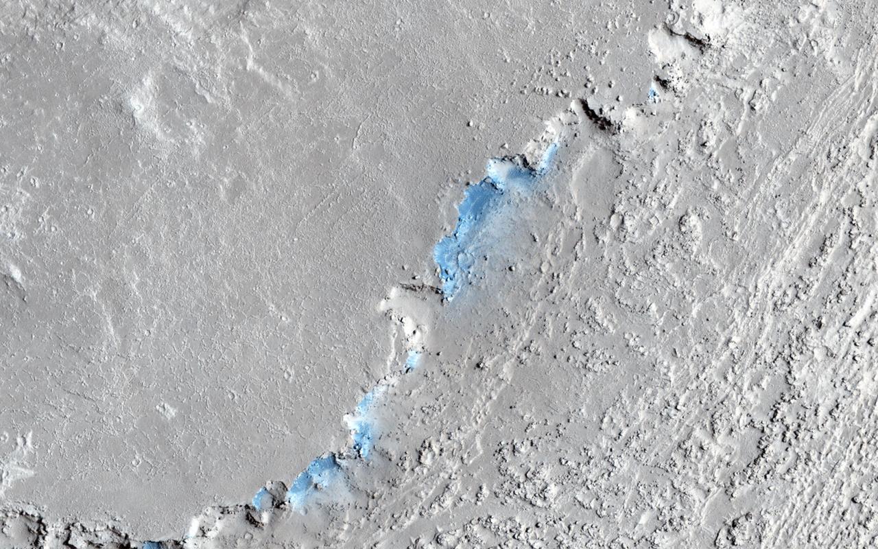 This image captured by NASA Mars Reconnaissance Orbiter shows a small channel cutting into young volcanic lavas in a region where massive catastrophic flooding took place in the relatively recent past. The Athabasca Valles region includes a vast lava flow, thought to be the youngest on Mars, with even younger outflow channels that were carved by running water. The source of the water is believed to be the Cerberus Fossae valleys to the north, which may have penetrated to an over-pressurized aquifer in the subsurface. Nowadays, erosion by gravity, wind, and frost gradually wears down the rims of the outflow channels. In this scene, we see dark materials along the channel rim that were probably exposed by this erosion. The dark materials are less red than the surrounding surface and so they appear blue in this enhanced color picture. Viewed close up, the dark materials show ripples that suggest they are made up of mobile sand. It is possible that this sand originated elsewhere and simply collected where we see it today, but the fact that sand is not found elsewhere in the scene suggest to us that it is eroding out of the volcanic layers at the retreating rim of the channel. Sand sources are important because mobile sand grains have only a limited lifetime, wearing down and chipping apart each time they impact the surface. Erosion of the volcanic materials in this region may provide sands to replace those that are destroyed. Few such sand sources have so far been identified on Mars. http://photojournal.jpl.nasa.gov/catalog/PIA18889
