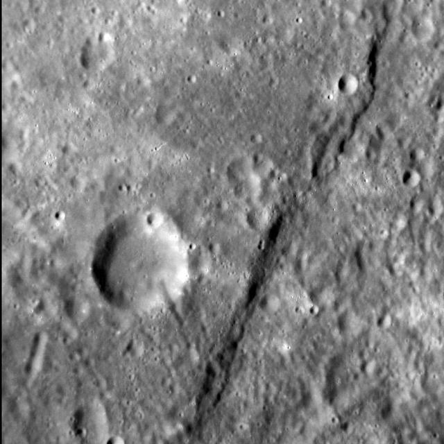 The cliff-like feature crossing this image from NASA MESSENGER spacecraft from top to bottom is one of Mercury famed lobate scarps, and is called Pourquoi-Pas Rupes.