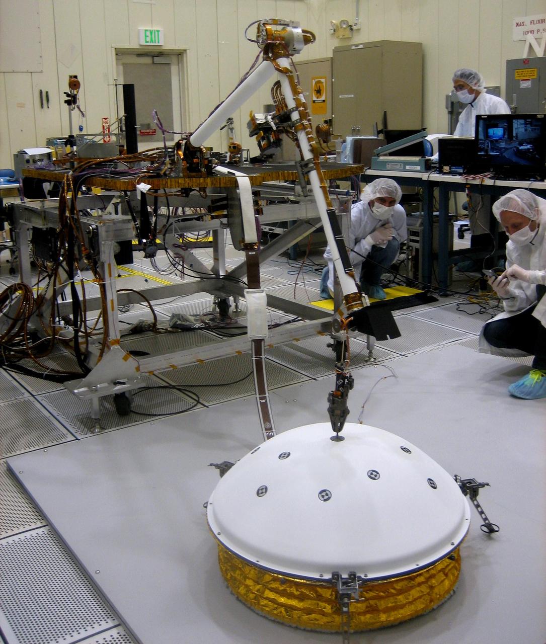 In the weeks after NASA's InSight mission reaches Mars in September 2016, the lander's arm will lift two key science instruments off the deck and place them onto the ground. This image shows testing of InSight's robotic arm inside a clean room at NASA's Jet Propulsion Laboratory, Pasadena, California, about two years before it will perform these tasks on Mars. InSight -- an acronym for Interior Exploration using Seismic Investigations, Geodesy and Heat Transport -- will launch in March 2016. It will study the interior of Mars to improve understanding of the processes that formed and shaped rocky planets, including Earth. One key instrument that the arm will deploy is the Seismic Experiment for Interior Structure, or SEIS. It is from France's national space agency (CNES), with components from Germany, Switzerland, the United Kingdom and the United States. In this scene, the arm has just deployed a test model of a protective covering for SEIS, the instrument's wind and thermal shield. The shield's purpose is to lessen disturbances that weather would cause to readings from the sensitive seismometer. Note: After thorough examination, NASA managers have decided to suspend the planned March 2016 launch of the Interior Exploration using Seismic Investigations Geodesy and Heat Transport (InSight) mission. The decision follows unsuccessful attempts to repair a leak in a section of the prime instrument in the science payload. http://photojournal.jpl.nasa.gov/catalog/PIA19144