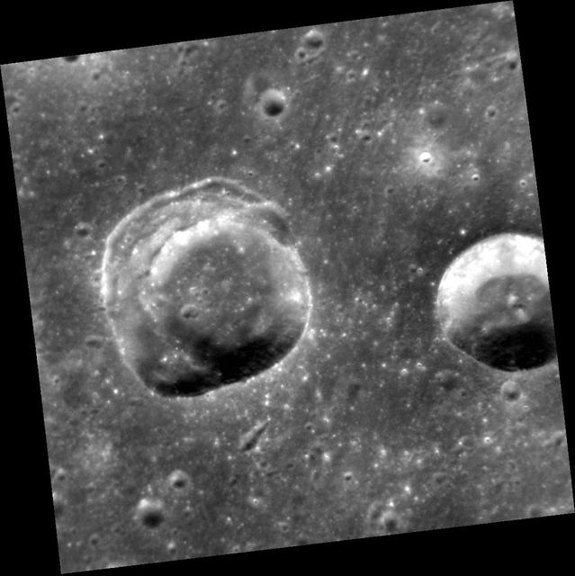 This view shows two craters in an area of smooth plains. The crater on the left presents an interesting geological puzzle. Note that about 90° of the rim (in the east, the right side) is sharp. But the remaining 270° of the circumference consists of a broad terrace, formed by slumping and inward movement of material. Why do you think that part of the rim and wall suffered slumping? Differences in the strength of the target material? (And, if so, caused by what?) The angle at which the impactor struck the surface? The topography of the surface? The presence of buried topography or structures? Local or regional tectonics? What additional data could help to solve this riddle? http://photojournal.jpl.nasa.gov/catalog/PIA19232
