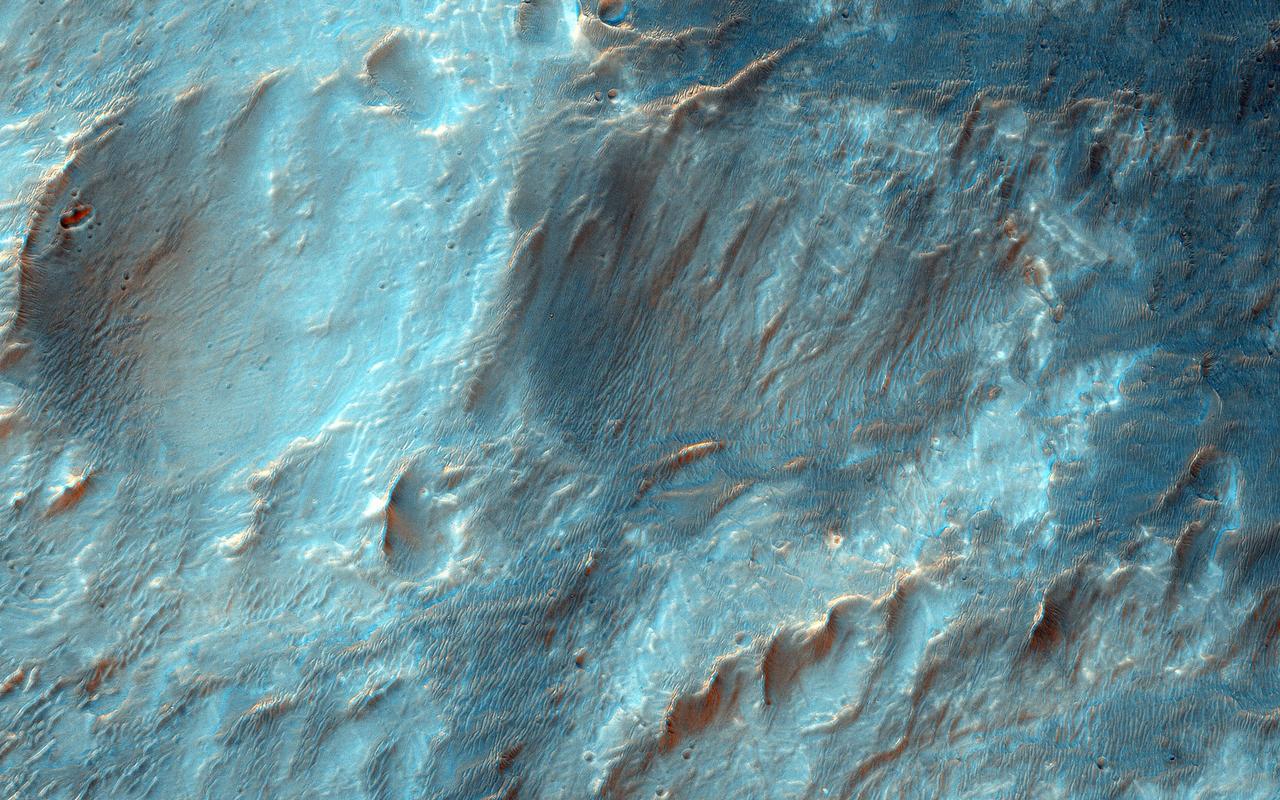 Bigbee is a 21 kilometer-diameter impact crater located on the northern rim of Holden crater in southern Margaritifer Terra, a region on Mars that is well known for its long record of water-rich activity as seen by NASA Mars Reconnaissance Orbiter.  he rim of Bigbee has been heavily modified from its original form, presumably by water and wind. Material eroded and removed from Bigbee's rim was transported and deposited to the crater interior. Some of the darker-toned material near Bigbee's northern rim has been incorporated into fan-shaped deposits with distinct margins at the outer part. The fan surfaces appear to lack obvious layering and channels.  The modification of Bigbee and other smaller craters on Holden's rim may have been contemporaneous with a proposed period of relatively late, water-driven activity that formed fans in Holden and other craters in Margaritifer Terra (see Grant and Wilson, 2012).  Note: The cutout is 3.5-kilometer across and shows dark fan-like deposits on left side of image at the base of a light-toned scarp.  http://photojournal.jpl.nasa.gov/catalog/PIA19296