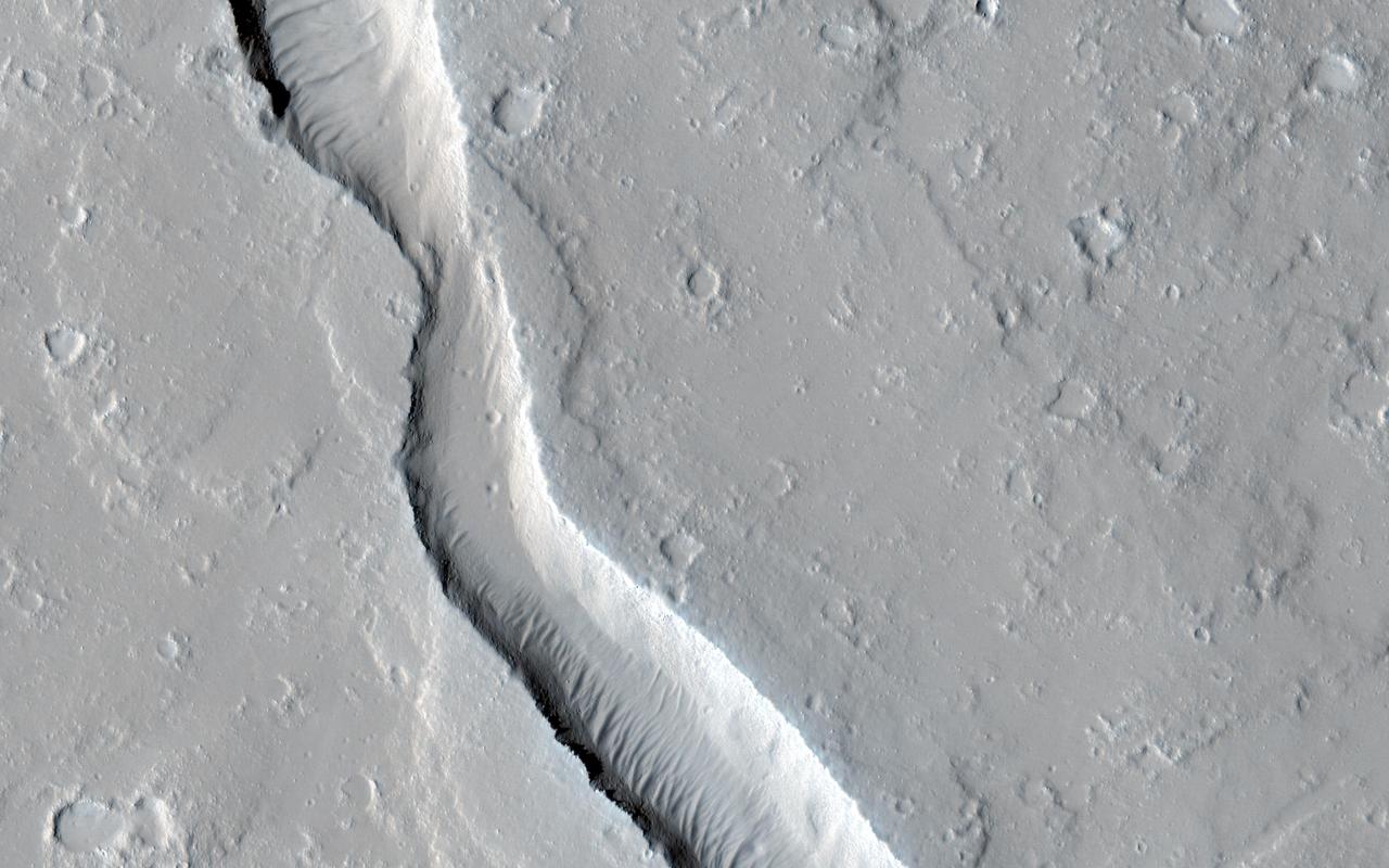 This image from NASA Mars Reconnaissance Orbiter shows a lava channel, which lies just to the east of the largest volcano in the solar system: Olympus Mons.  The channel appears to be discontinuous, meaning it disappears several times throughout its length, but in fact, it is likely that the channel continues underground as a lava tube.  These are relatively common features at terrestrial volcanic centers, such as the Big Island of Hawai'i. The channel appears to have been infilled with dust and sand, so that the entrance to a lava tube cave is no longer visible at this particular location; fortunately this has been observed elsewhere on Mars.  http://photojournal.jpl.nasa.gov/catalog/PIA19299