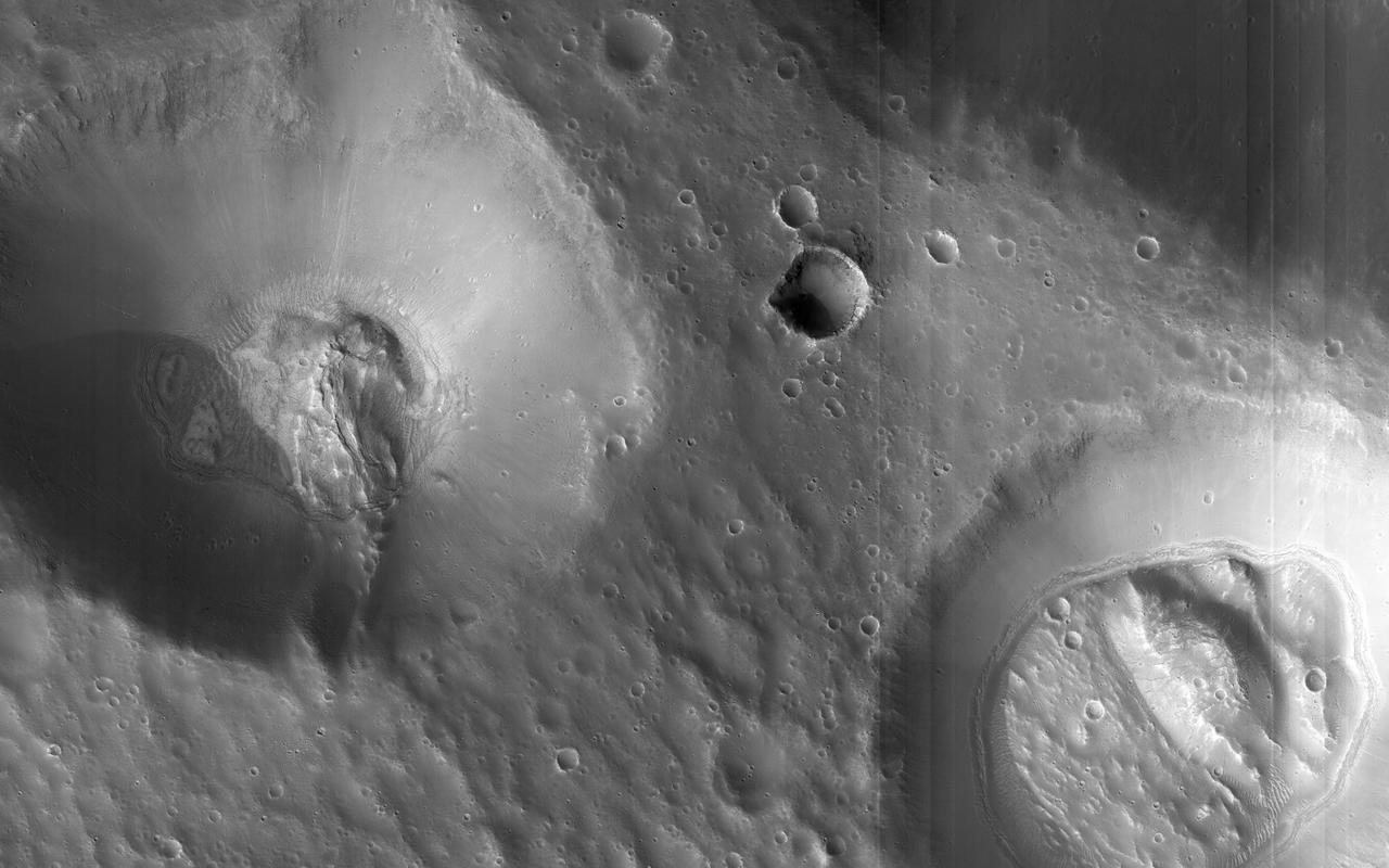 This image from NASA Mars Reconnaissance Orbiter of craters near Nilokeras Scopulus shows two pits partially filled with lumpy material, probably trapped dust that blew in from the atmosphere. This image shows two pits partially filled with lumpy material, probably trapped dust that blew in from the atmosphere. The pits themselves resemble impact craters, but they are part of a chain of similar features aligned with nearby faults, so they could be collapse features instead. Note also the tracks left by rolling boulders at the bottom of the craters. Nilokeras Scopulus is the name for the cliff, about 756 kilometers long, in the northern hemisphere of Mars where these craters are located. It was named based on an albedo (brightness) feature mapped by astronomer E. M. Antoniadi in 1930. http://photojournal.jpl.nasa.gov/catalog/PIA19304