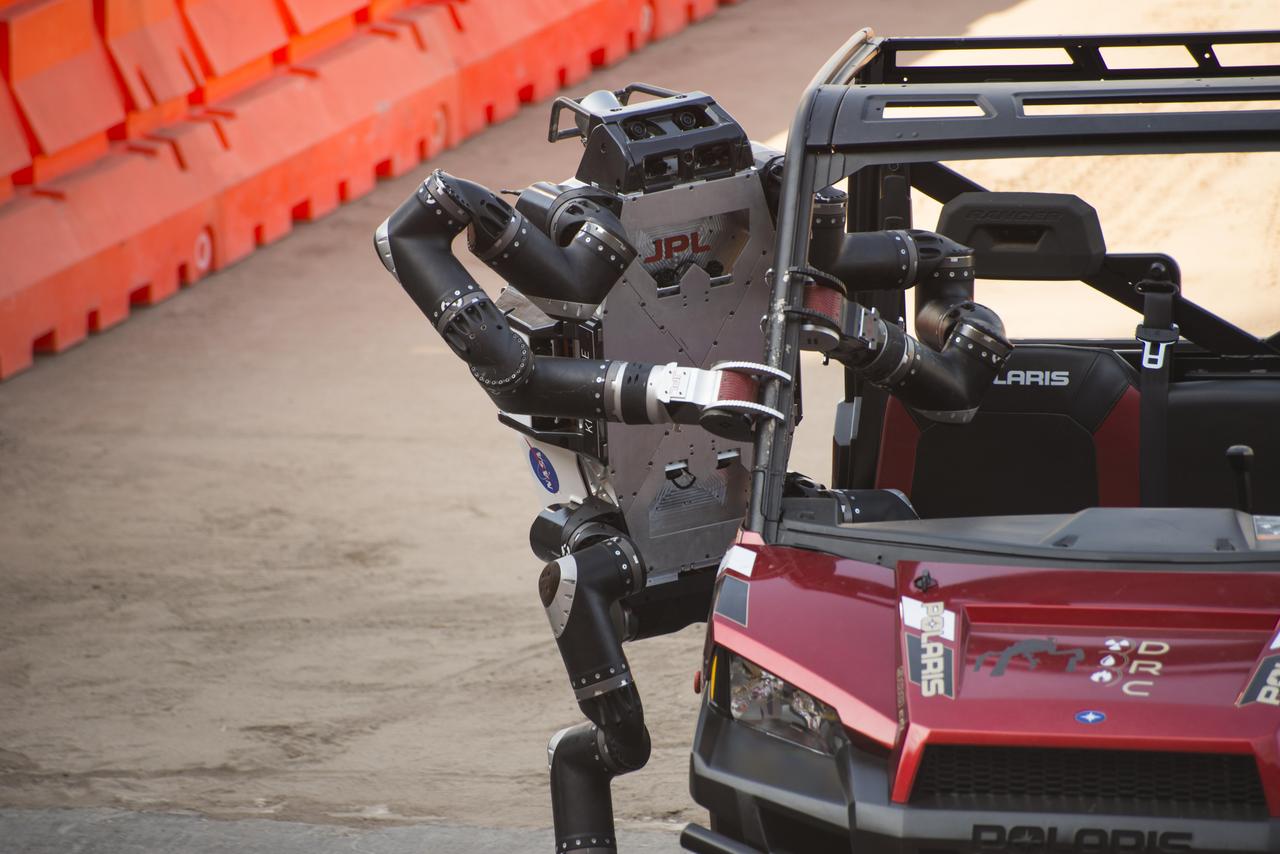 JPL's RoboSimian exits its vehicle following a brief drive through a slalom course at the DARPA Robotics Challenge in Pomona, California. This image was taken June 6, 2015.  http://photojournal.jpl.nasa.gov/catalog/PIA19324
