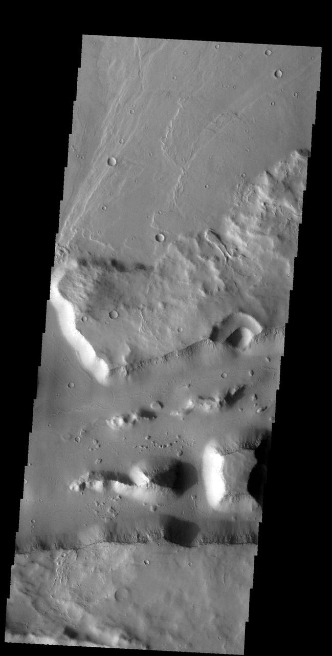The linear wall at the bottom of this image from NASA 2001 Mars Odyssey spacecraft is a fault. The linear depression caused by faulting is part of a long depression called Mangala Fossae. Orbit Number: 58979 Latitude: -17.9823 Longitude: 210.806 Instrument: VIS Captured: 2015-04-01 00:54 http://photojournal.jpl.nasa.gov/catalog/PIA19468