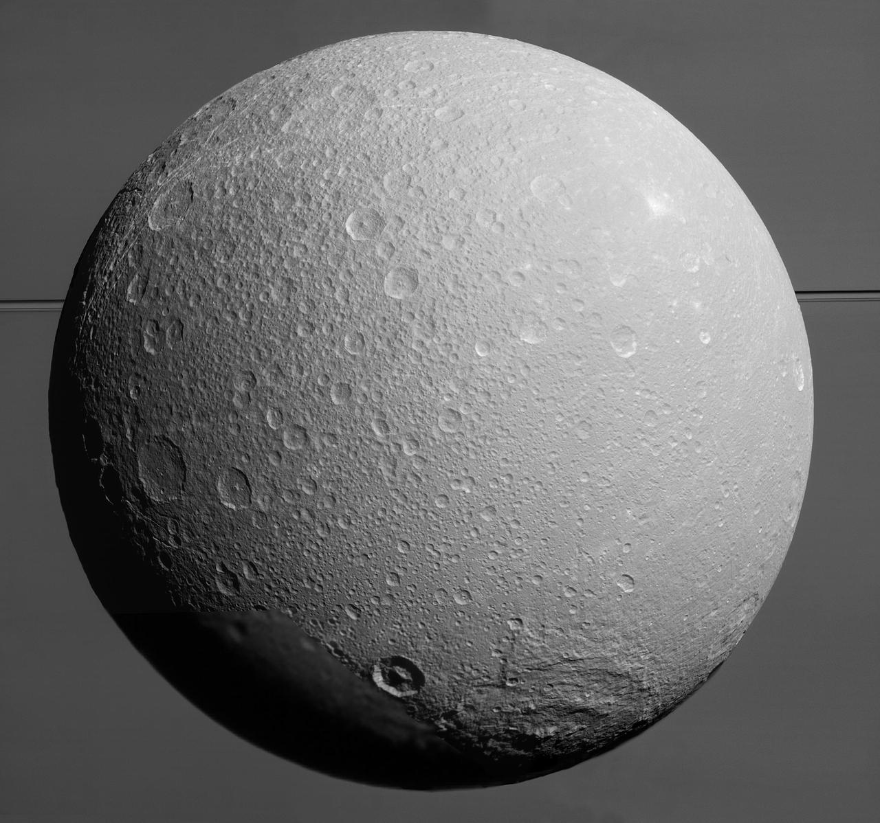 This view from NASA Cassini spacecraft looks toward Saturn icy moon Dione, with giant Saturn and its rings in the background, just prior to the mission final close approach to the moon on August 17, 2015.  At lower right is the large, multi-ringed impact basin named Evander, which is about 220 miles (350 kilometers) wide. The canyons of Padua Chasma, features that form part of Dione's bright, wispy terrain, reach into the darkness at left.  Imaging scientists combined nine visible light (clear spectral filter) images to create this mosaic view: eight from the narrow-angle camera and one from the wide-angle camera, which fills in an area at lower left. The scene is an orthographic projection centered on terrain at 0.2 degrees north latitude, 179 degrees west longitude on Dione. An orthographic view is most like the view seen by a distant observer looking through a telescope. North on Dione is up.  The view was acquired at distances ranging from approximately 106,000 miles (170,000 kilometers) to 39,000 miles (63,000 kilometers) from Dione and at a sun-Dione-spacecraft, or phase, angle of 35 degrees. Image scale is about 1,500 feet (450 meters) per pixel.  http://photojournal.jpl.nasa.gov/catalog/PIA19650