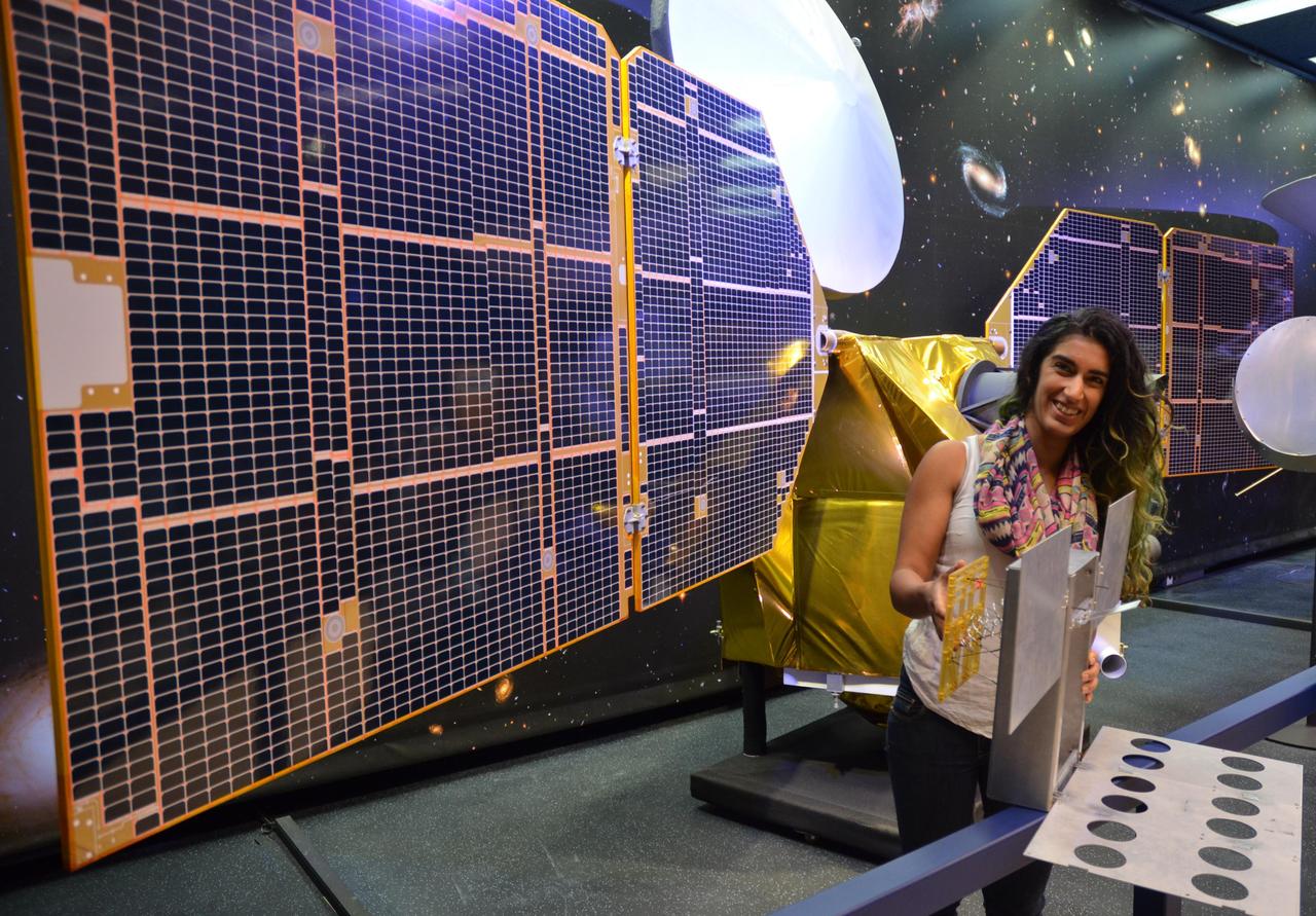 The full-scale mock-up of NASA's MarCO CubeSat held by Farah Alibay, a systems engineer at NASA's Jet Propulsion Laboratory, is dwarfed by the one-half-scale model of NASA's Mars Reconnaissance Orbiter behind her.  MarCO, short for Mars Cube One, is the first interplanetary use of CubeSat technologies for small spacecraft. JPL is preparing two MarCO twins for launch in March 2016. They will ride along on an Atlas V launch vehicle lifting off from Vandenberg Air Force Base, California, with NASA's next Mars lander, InSight. MarCO is a technology demonstration aspect of the InSight mission.  The mock-up in the photo is in a configuration to show the deployed position of components that correspond to MarCO's two solar panels and two antennas. During launch, those components will be stowed for a total vehicle size of about 14.4 inches (36.6 centimeters) by 9.5 inches (24.3 centimeters) by 4.6 inches (11.8 centimeters).  After launch, the two MarCO CubeSats and InSight will be navigated separately to Mars. The MarCO twins will fly past the planet in September 2016 just as InSight is descending through the atmosphere and landing on the surface. MarCO is a technology demonstration to relay communications from InSight to Earth during InSight's descent and landing. InSight communications during that critical period will also be recorded by NASA's Mars Reconnaissance Orbiter for delayed transmission to Earth.  InSight -- an acronym for Interior Exploration using Seismic Investigations, Geodesy and Heat Transport -- will study the interior of Mars to improve understanding of the processes that formed and shaped rocky planets, including Earth.  Note: After thorough examination, NASA managers have decided to suspend the planned March 2016 launch of the Interior Exploration using Seismic Investigations Geodesy and Heat Transport (InSight) mission. The decision follows unsuccessful attempts to repair a leak in a section of the prime instrument in the science payload.  http://photojournal.jpl.nasa.gov/catalog/PIA19671
