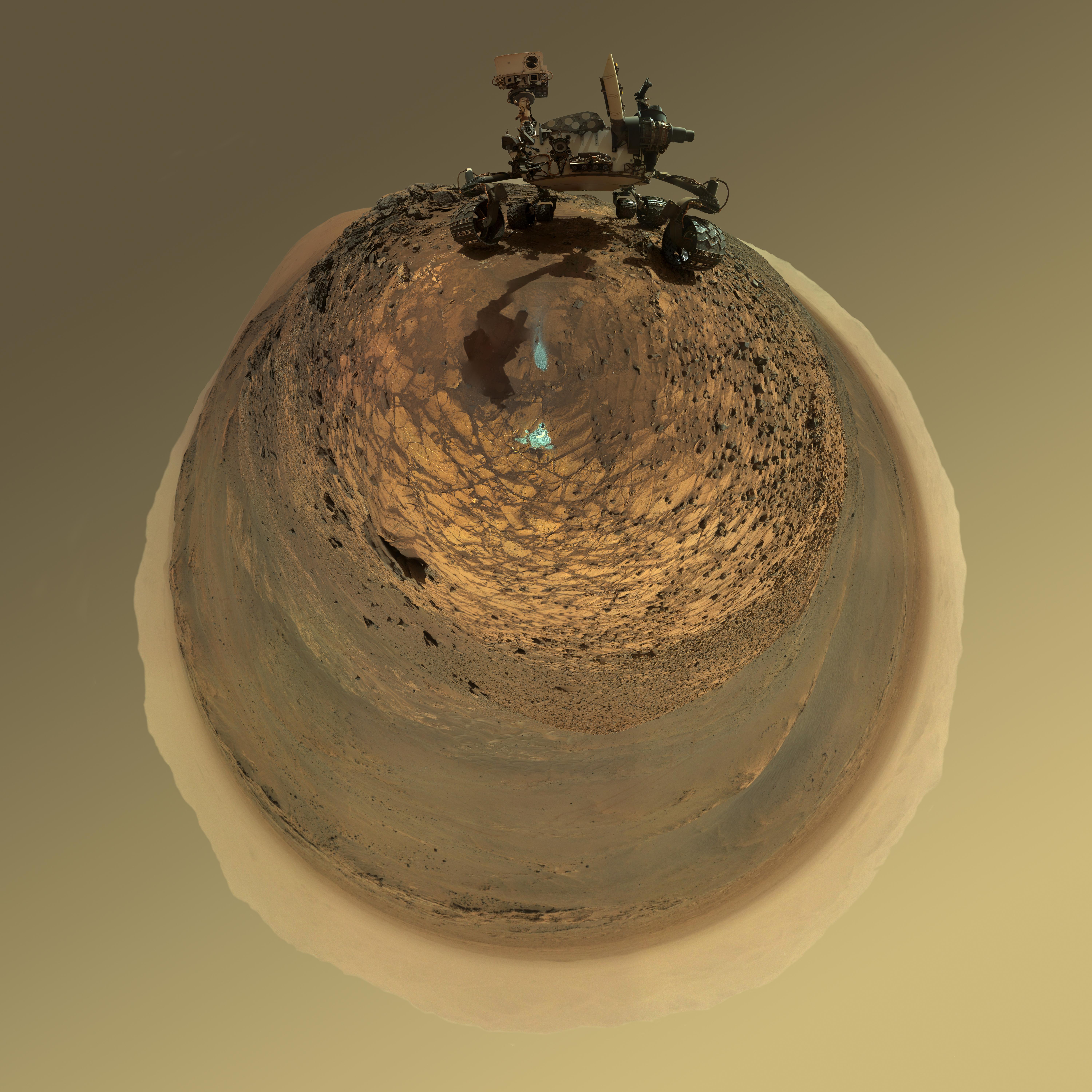 This version of a self-portrait of NASA's Curiosity Mars rover at a drilling site called "Buckskin" on lower Mount Sharp is presented as a stereographic projection, which shows the horizon as a circle.  It is a mosaic assembled from the same set of 92 component raw images used for the flatter-horizon version at PIA19807. The component images were taken by Curiosity's Mars Hand Lens Imager (MAHLI) on Aug. 5, 2015, during the 1,065th Martian day, or sol, of the rover's work on Mars.  Curiosity drilled the hole at Buckskin during Sol 1060 (July 30, 2015). Two patches of pale, powdered rock material pulled from inside Buckskin are visible in this scene, in front of the rover. The patch closer to the rover is where the sample-handling mechanism on Curiosity's robotic arm dumped collected material that did not pass through a sieve in the mechanism. Sieved sample material was delivered to laboratory instruments inside the rover. The patch farther in front of the rover, roughly triangular in shape, shows where fresh tailings spread downhill from the drilling process. The drilled hole, 0.63 inch (1.6 centimeters) in diameter, is at the upper point of the tailings.  The rover is facing northeast, looking out over the plains from the crest of a 20-foot (6-meter) hill that it climbed to reach the "Marias Pass" area. The upper levels of Mount Sharp are visible behind the rover, while Gale Crater's northern rim dominates most of the rest of the horizon.the horizon on the left and right of the mosaic.  MAHLI is mounted at the end of the rover's robotic arm. For this self-portrait, the rover team positioned the camera lower in relation to the rover body than for any previous full self-portrait of Curiosity. The assembled mosaic does not include the rover's arm beyond a portion of the upper arm held nearly vertical from the shoulder joint. Shadows from the rest of the arm and the turret of tools at the end of the arm are visible on the ground. With the wrist motions and turret rotations used in pointing the camera for the component images, the arm was positioned out of the shot in the frames or portions of frames used in this mosaic.  MAHLI was built by Malin Space Science Systems, San Diego. NASA's Jet Propulsion Laboratory, a division of the California Institute of Technology in Pasadena, manages the Mars Science Laboratory Project for the NASA Science Mission Directorate, Washington. JPL designed and built the project's Curiosity rover.  http://photojournal.jpl.nasa.gov/catalog/PIA19806