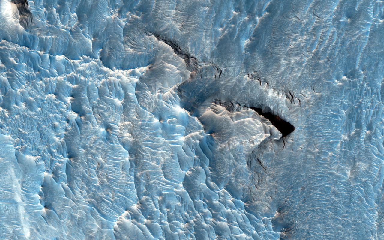 The objective of this observation from NASA Mars Reconnaissance Orbiter is to examine a light-toned deposit in a region of what is called "chaotic terrain."   There are indications of layers in the image. Some shapes suggest erosion by a fluid moving north and south. The top of the light-toned deposit appears rough, in contrast to the smoothness of its surroundings.   http://photojournal.jpl.nasa.gov/catalog/PIA19844