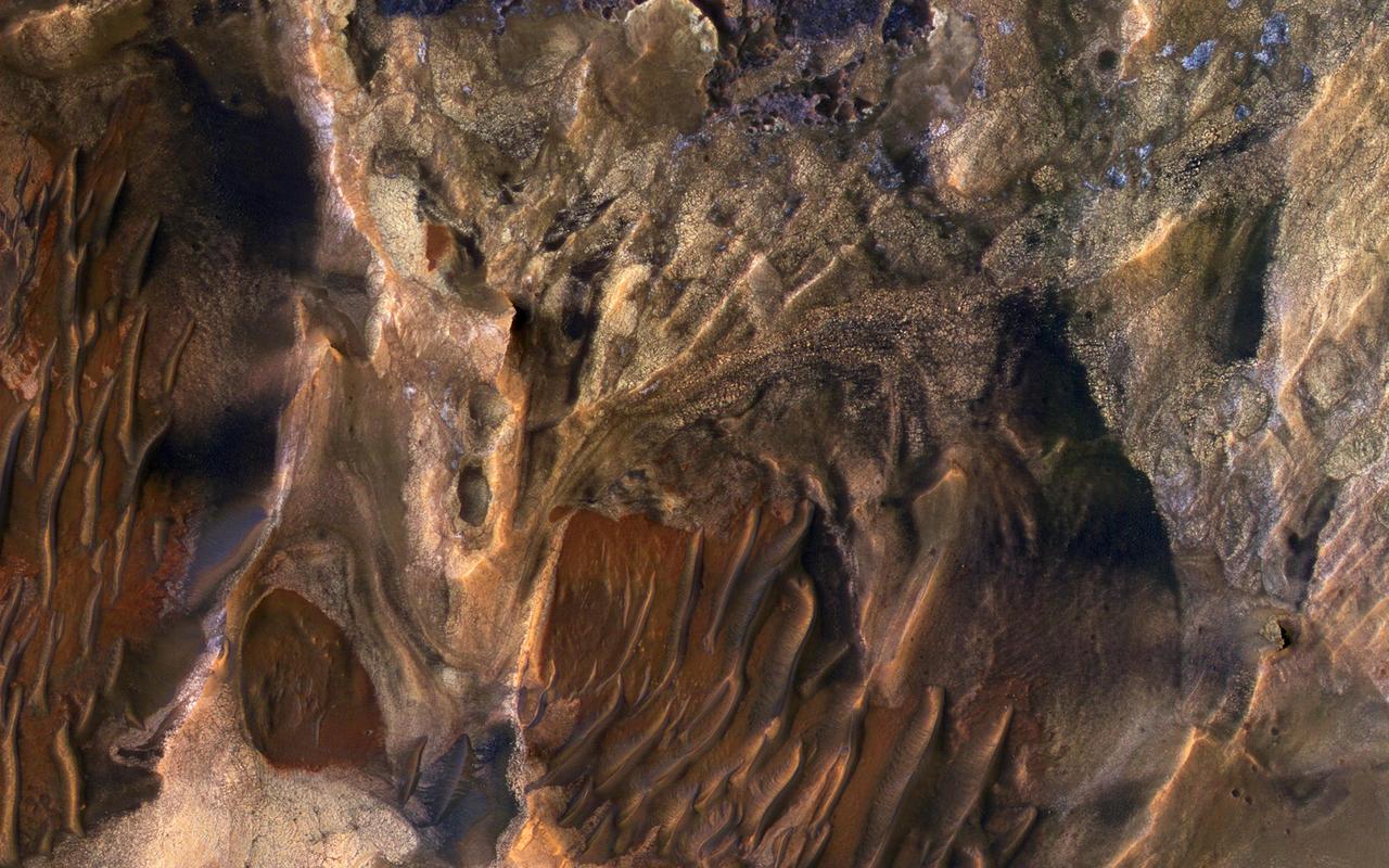 This scene captured by NASA Mars Reconnaissance Orbiter includes chaotic deposits with a wide range of colors. The deposits are distinctive with both unique colors and small-scale textures such as fracture patterns.  These are probably sedimentary rocks, transported and deposited in water or air. The original layers may have been jumbled in a landslide. Dark or reddish sand dunes cover some of the bedrock.  http://photojournal.jpl.nasa.gov/catalog/PIA19860